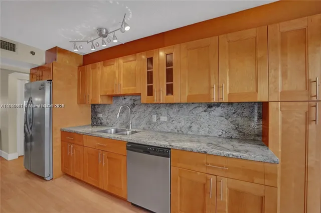 a kitchen with stainless steel appliances granite countertop a refrigerator and a sink