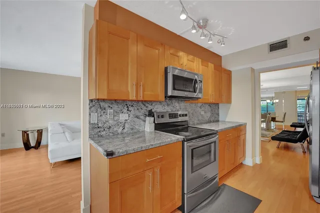 a kitchen with stainless steel appliances granite countertop a stove a sink and a microwave