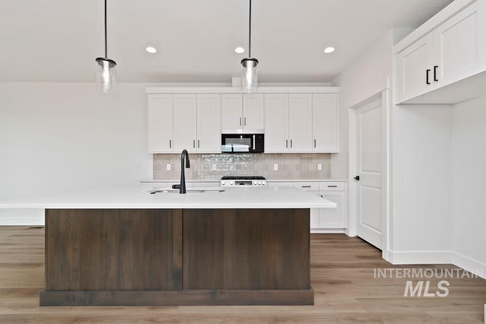 744 South Calhoun Lane Star, ID 83669 - Photo 4 of 34 Kitchen with white cabinetry, stainless steel appliances, pendant lighting, light wood-style floors, and a center island with sink