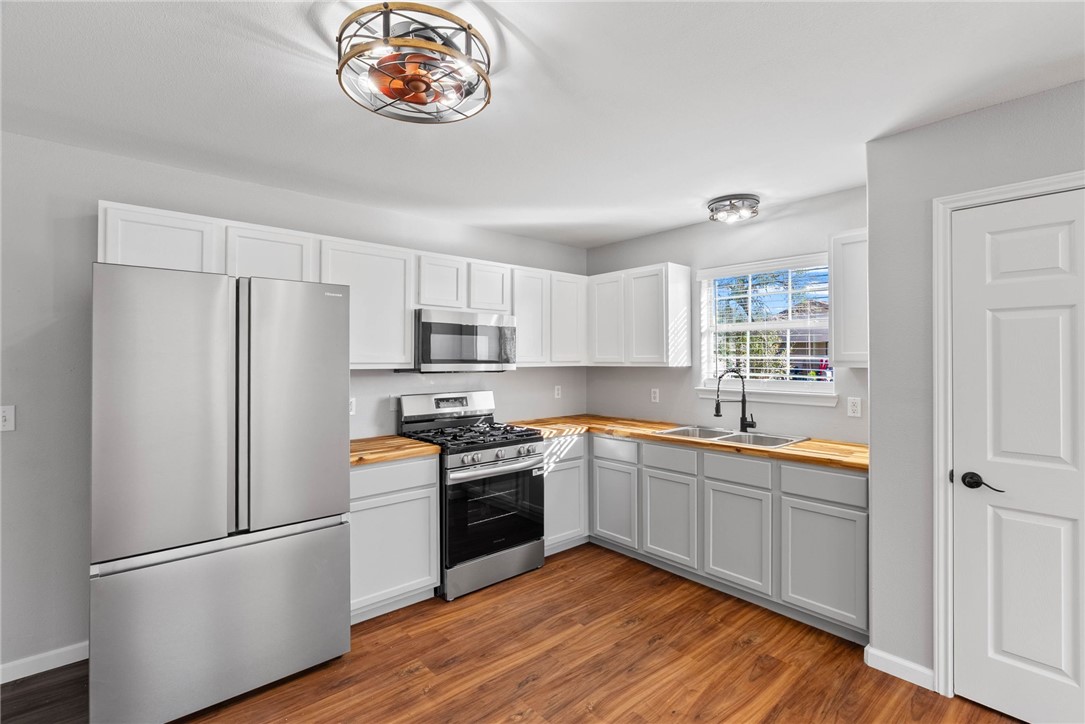 804 Ave B Street Sinton, TX 78387 - Photo 4 of 40 a kitchen with stainless steel appliances a refrigerator a sink and wooden floors