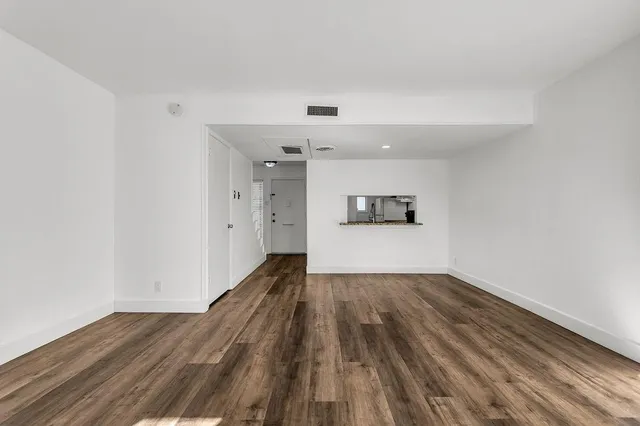 a view of a big room with wooden floor and kitchen view