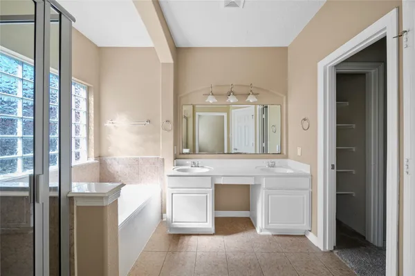 a spacious bathroom with a tub shower and windows