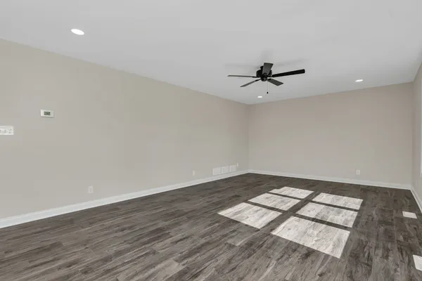 an empty room with wooden floor and ceiling fan