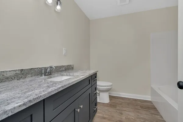 a bathroom with a granite countertop sink a toilet and bathtub