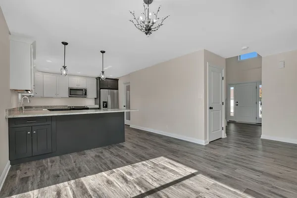 a kitchen with stainless steel appliances granite countertop a refrigerator a sink dishwasher a stove and white cabinets with wooden floor