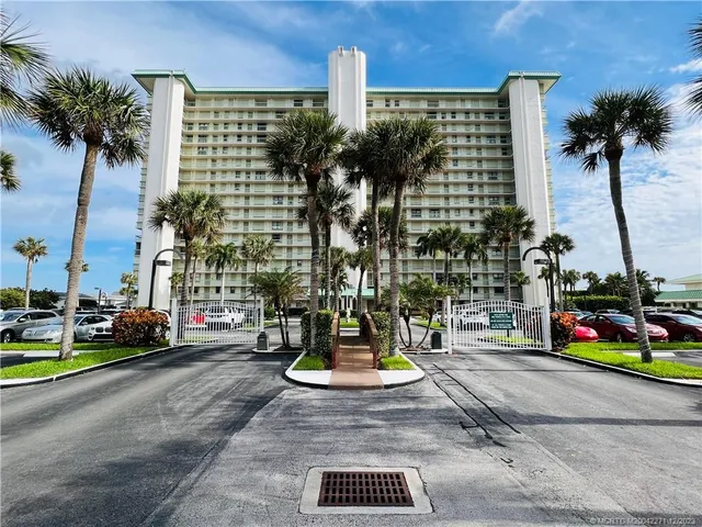 a kitchen with stainless steel appliances kitchen island granite countertop a refrigerator a stove a sink a dining table and chairs with wooden floor