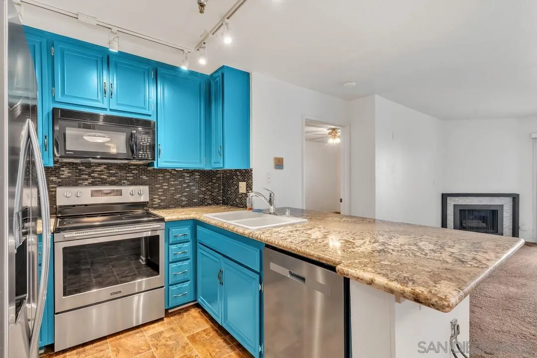5745 Friars Road, Unit 104 San Diego, CA 92110 - Photo 11 of 38 a kitchen with granite countertop wood cabinets stove and microwave
