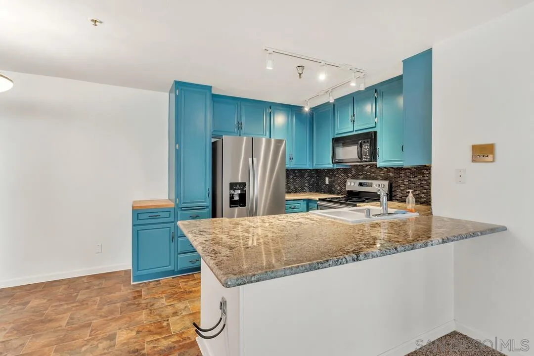 5745 Friars Road, Unit 104 San Diego, CA 92110 - Photo 14 of 38 a kitchen with stainless steel appliances granite countertop a refrigerator a stove a sink a washer and dryer