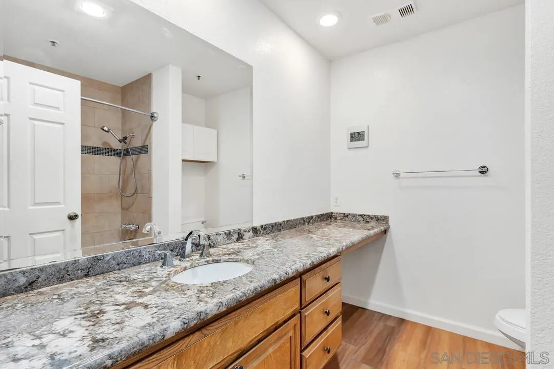 5745 Friars Road, Unit 104 San Diego, CA 92110 - Photo 28 of 38 a bathroom with a granite countertop sink and a mirror