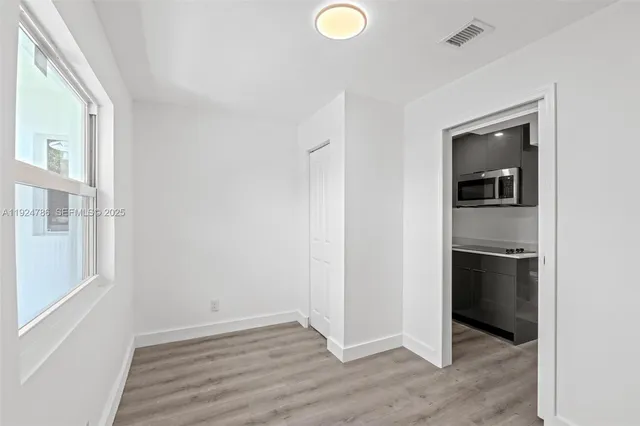 a view of an empty room with wooden floor and a window