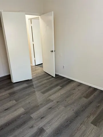 an empty room with wooden floor and mirror