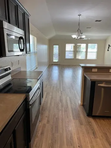 a kitchen with kitchen island granite countertop a stove top oven a sink a counter space and cabinets