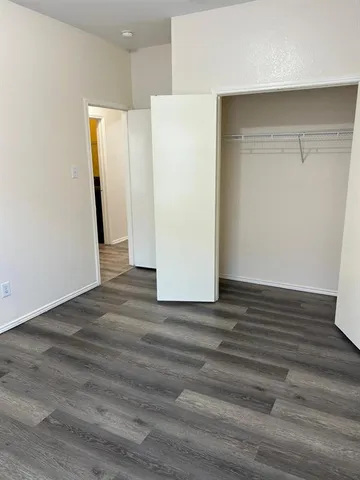 a view of an empty room with wooden floor and closet