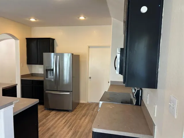 a kitchen with granite countertop a refrigerator and a stove top oven