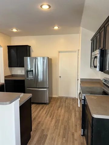 a kitchen with granite countertop a refrigerator and a stove top oven
