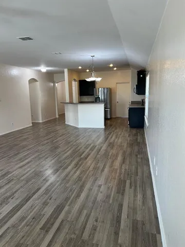 a view of a big room with wooden floor and kitchen