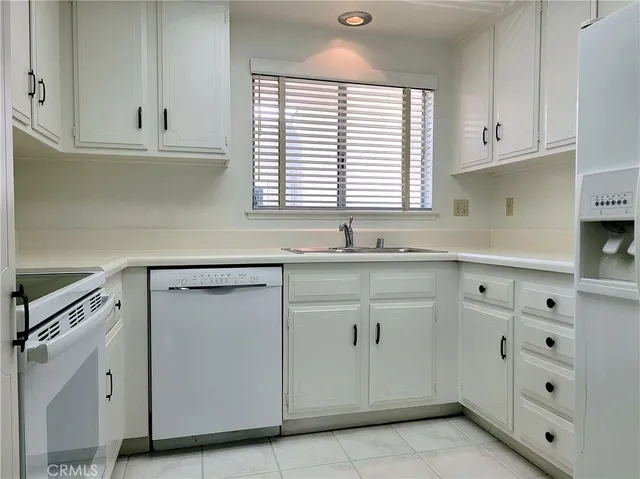 a kitchen with granite countertop white cabinets and a window