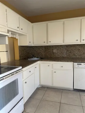 a kitchen with granite countertop white cabinets and white appliances
