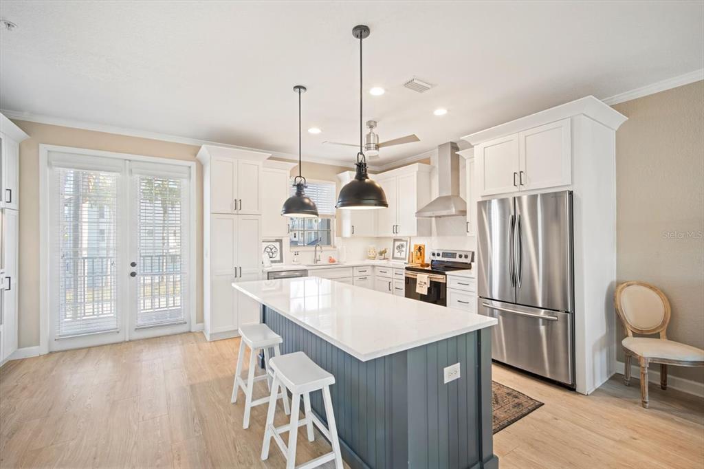 135 Bath Club Circle North Redington Beach, FL 33708 - Photo 9 of 45 a kitchen with stainless steel appliances granite countertop a refrigerator a sink dishwasher a stove and a dining table with wooden floor