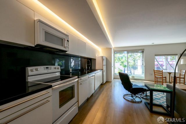 a kitchen with stainless steel appliances a stove a sink a microwave cabinets and a dining table