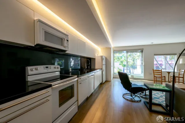 a kitchen with stainless steel appliances a stove a sink a microwave cabinets and a dining table