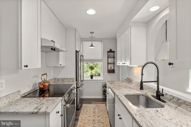 a kitchen with granite countertop a sink a stove and refrigerator