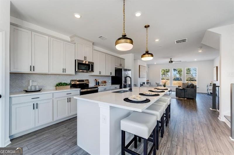 3276 Durston Dacula, GA 30019 - Photo 2 of 7 a kitchen with a sink a stove and chairs with wooden floor