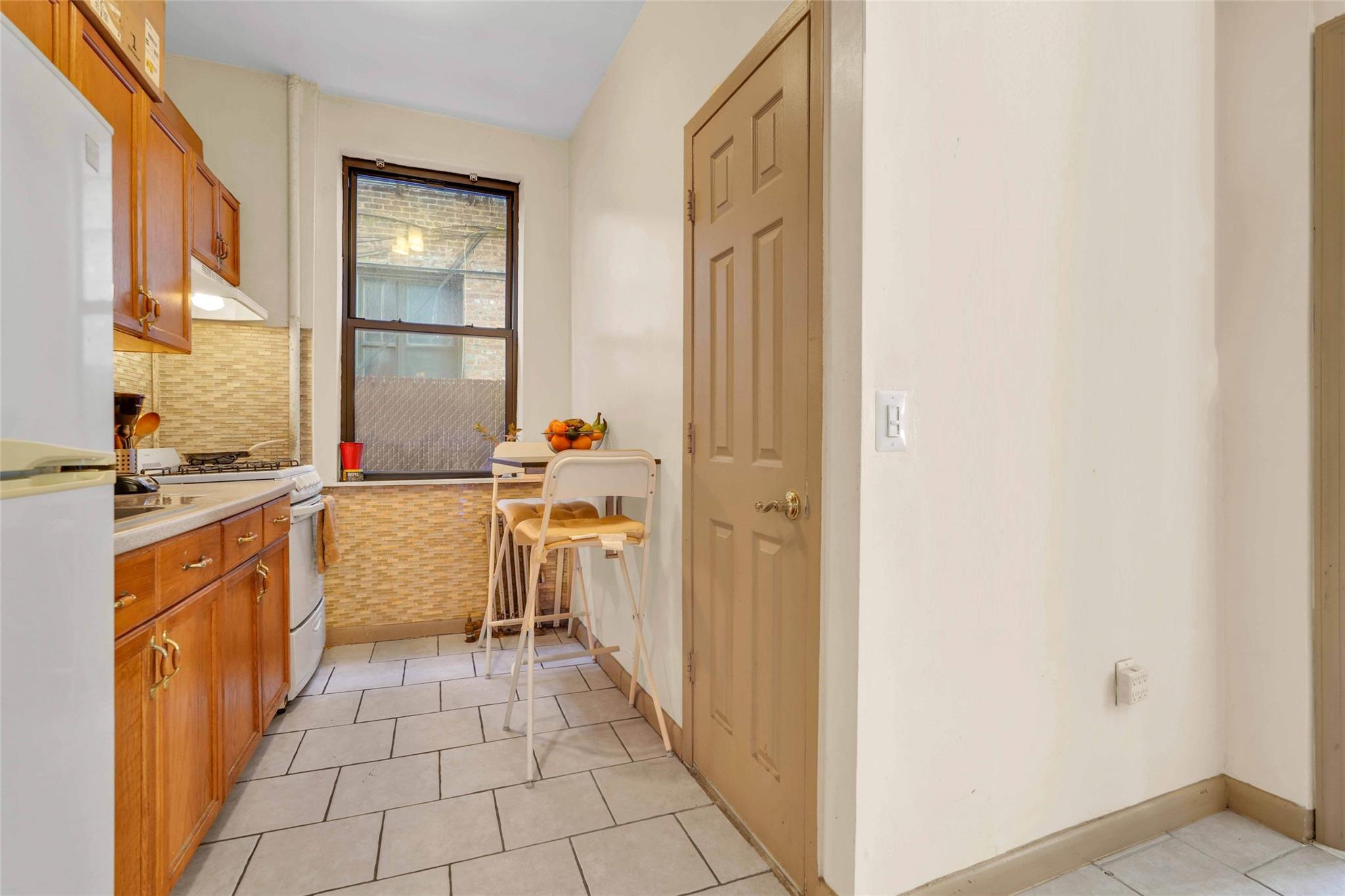 2146 Cortelyou Road, Unit 1R Brooklyn, NY 11226 - Photo 7 of 12 Kitchen with light countertops, brown cabinets, under cabinet range hood, gas range, and light tile patterned floors