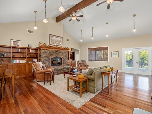 a living room with furniture kitchen view and a wooden floor
