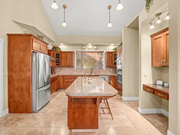 a large kitchen with kitchen island a sink a stove a refrigerator and a dining table with wooden floor