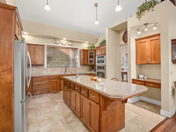 a kitchen with granite countertop a table chairs stove and refrigerator