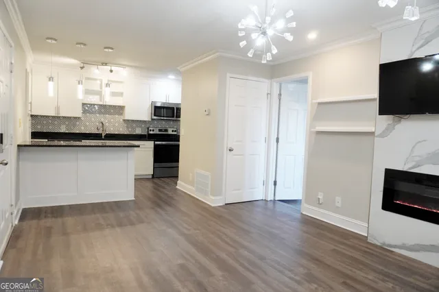 a kitchen with stainless steel appliances granite countertop a stove top oven a sink dishwasher and a refrigerator with wooden floor