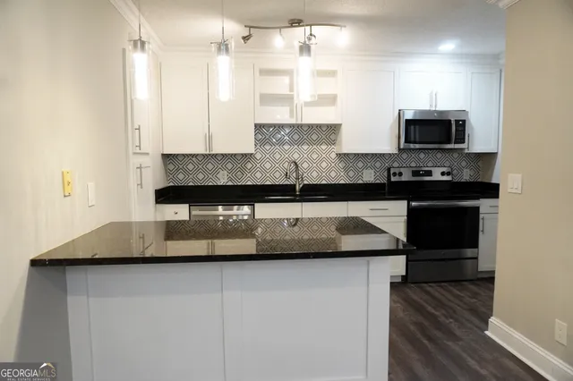a kitchen with kitchen island granite countertop a sink and a stove top oven with wooden floor