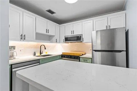 a kitchen with stainless steel appliances a refrigerator sink and white cabinets