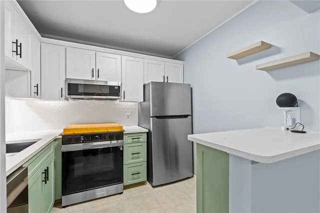 a kitchen with refrigerator a microwave a stove and white cabinets