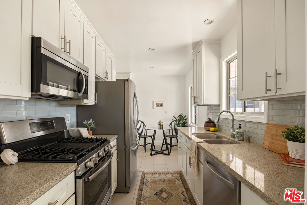 13610 Bracken Street Arleta, CA 91331 - Photo 10 of 23 a kitchen with stainless steel appliances granite countertop a stove top oven a sink dishwasher and a microwave oven with large wooden cabinets