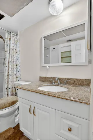 a bathroom with a granite countertop toilet sink and mirror