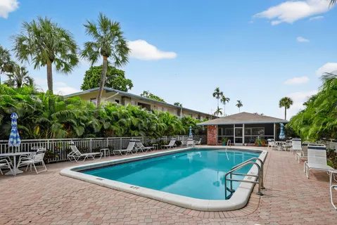 a view of a swimming pool with lawn chairs under an umbrella