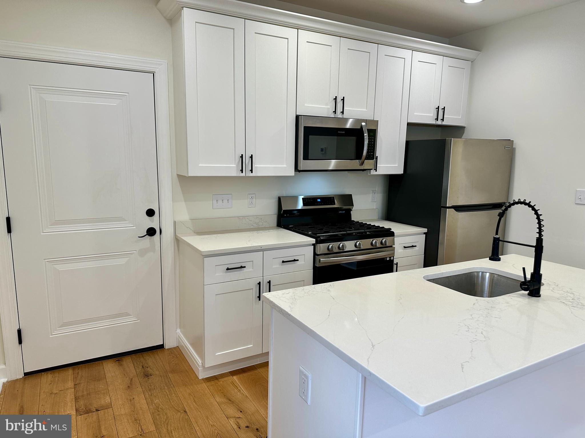 2009 North Reese Street, Unit 8B Philadelphia, PA 19122 - Photo 5 of 12 a kitchen with stainless steel appliances white cabinets and a sink