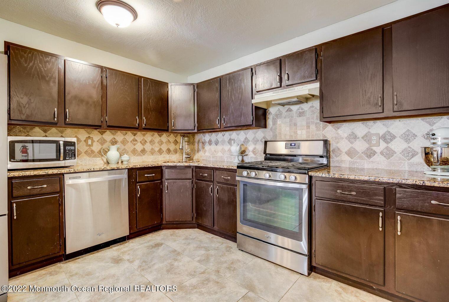 123 Hyacinth Lane Freehold, NJ 07728 - Photo 9 of 28 a kitchen with granite countertop wooden cabinets and stainless steel appliances