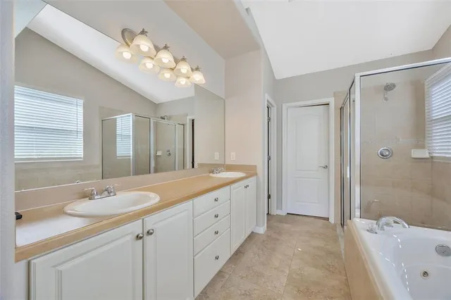 a spacious bathroom with a granite countertop sink a mirror a shower and a bathtub