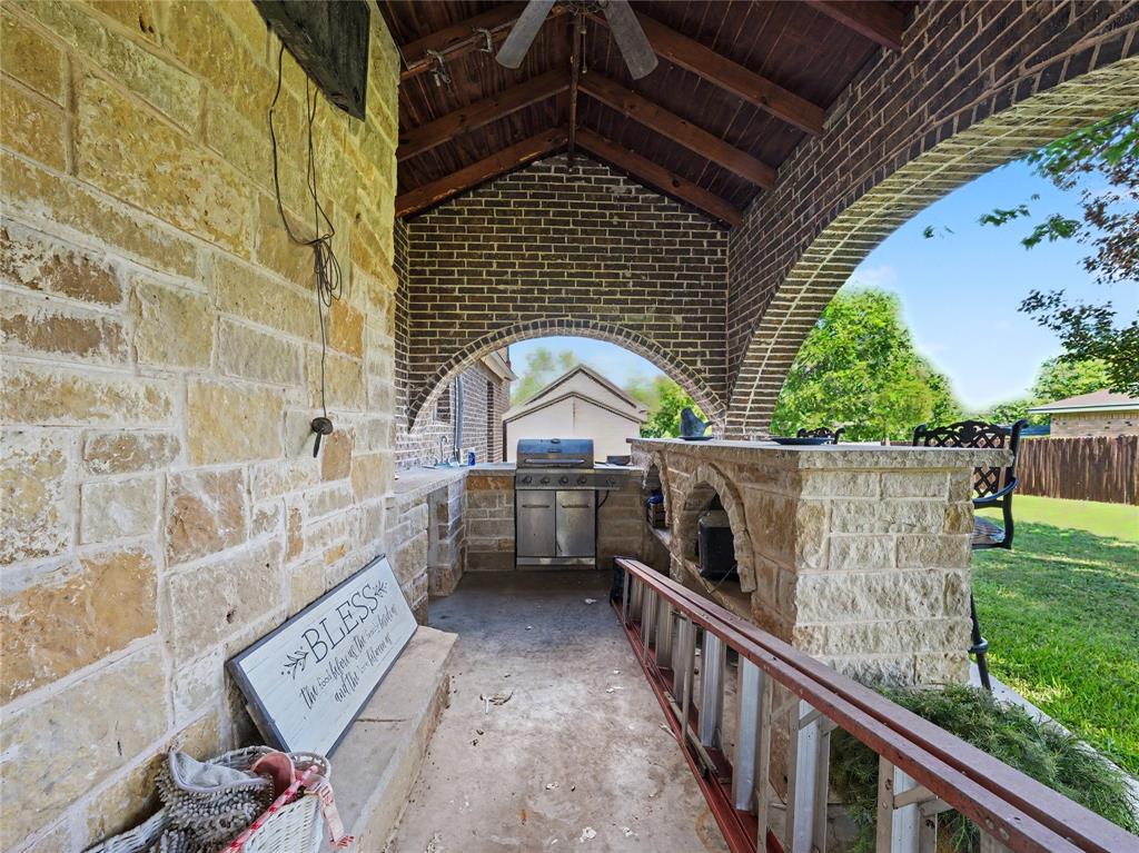 6701 Nauert Road Forest Hill, TX 76140 - Photo 39 of 40 Covered outdoor kitchen featuring stone construction, brick archways, a wood-plank ceiling, and a built-in grill