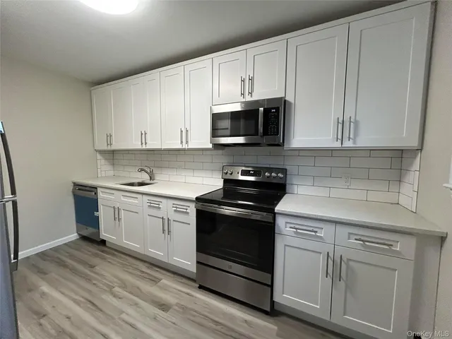 a kitchen with stainless steel appliances granite countertop a stove a sink and white cabinets
