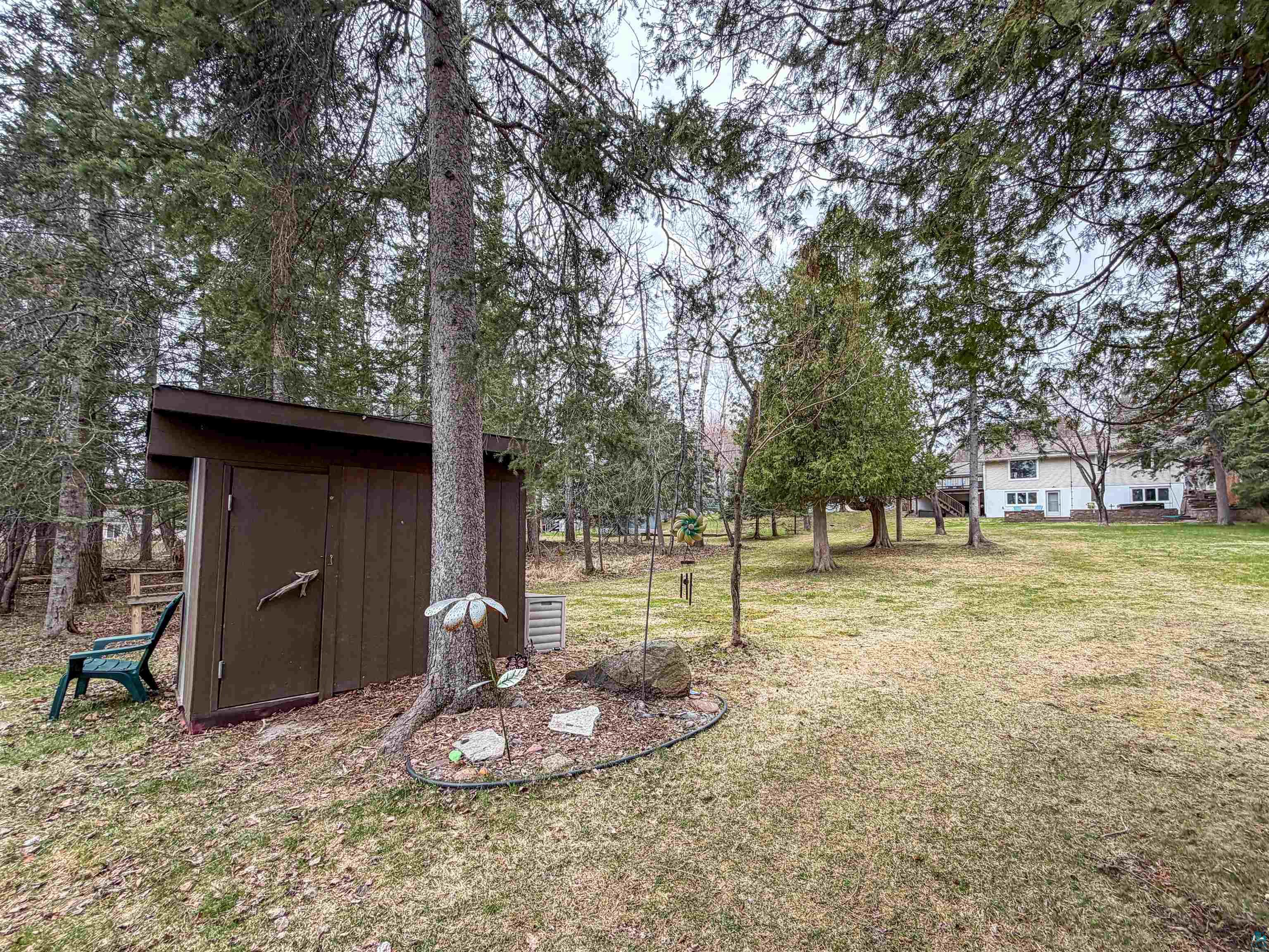 3704 Greysolon Road Duluth, MN 55804 - Photo 50 of 51 Expansive backyard featuring a brown wooden storage shed, mature evergreen trees, and a manicured lawn
