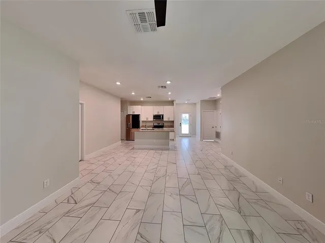 a view of empty room with kitchen
