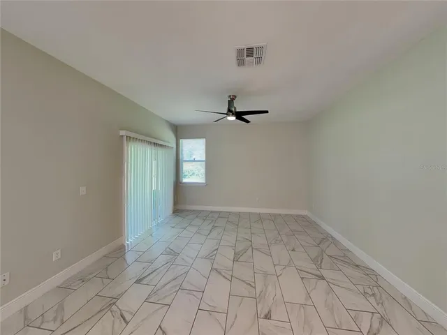 a view of an empty room with window and chandelier fan