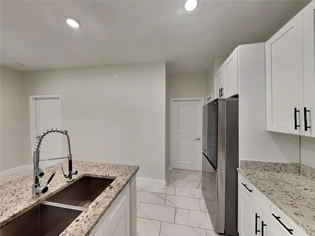 a kitchen with kitchen island granite countertop a sink stove and refrigerator