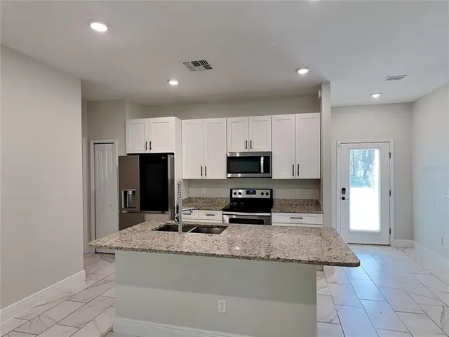 a kitchen with granite countertop a sink and stainless steel appliances