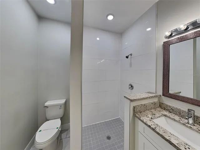 a bathroom with a granite countertop sink a toilet and shower
