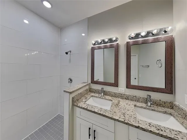 a bathroom with a granite countertop sink a large mirror and a shower